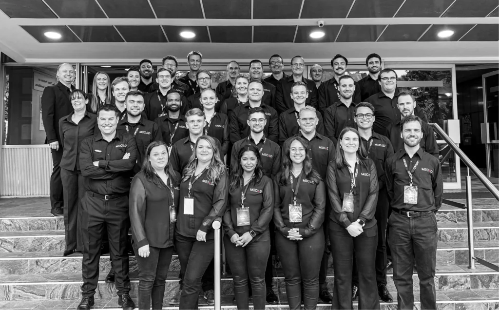 Black and white photograph capturing the MECAD Centurion team posing in front of the CSIR International Convention Centre after the successful 2023 MECAD Accelerate event.